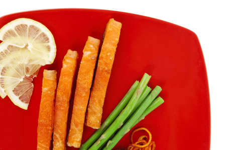 grilled salmon slices with asparagus lemon and fried orange peel on red plate isolated over white backgroundの写真素材