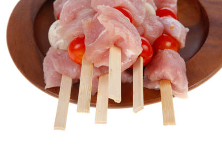 fresh raw meat fillet shish kebab turkey pork pink on skewers tomatoes mushrooms on wooden dish isolated over white backgroundの写真素材