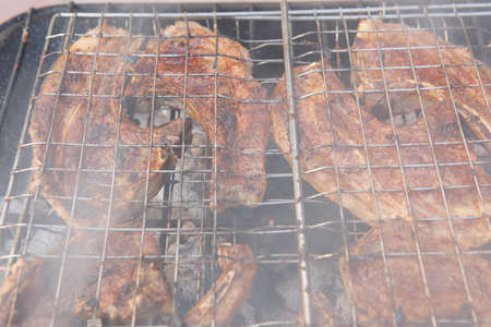 fresh raw lamb ribs on meat holder over fire burned churcoal with vegetable shish kebab on side outdoor partyの写真素材