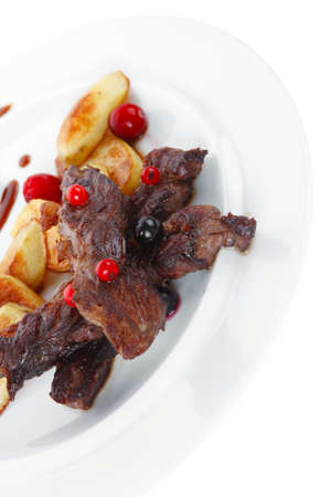 grilled beef meat with berries fried potatoes and cherry under sweet honey sauce on white plate isolated over white backgroundの写真素材