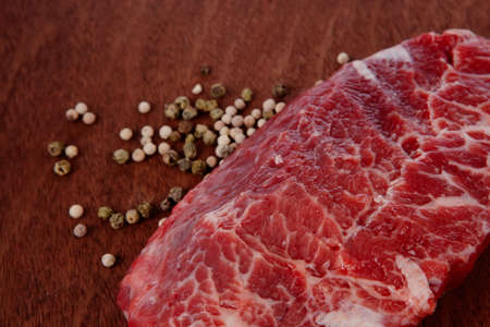 fresh raw beef meat steak with white and green peppercorn spice on walnut tableの写真素材