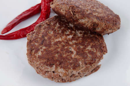 fresh juicy beef meat hamburger with dry pepper on white plate over tablecloth with cutlery