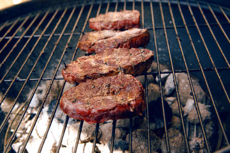 fresh raw beef fillet steak red meat on big round barbecue brazier black grid full burned charcoalの写真素材