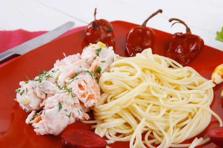 mediterranean cuisine: fresh rose wild salmon baked in cream cheese sauce with italian pasta and red hot pepper on plate over white wooden table with vegetable saladの写真素材