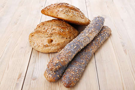delicacy french rye breads and baguettes topped with sunflower and poppy seeds over wooden table