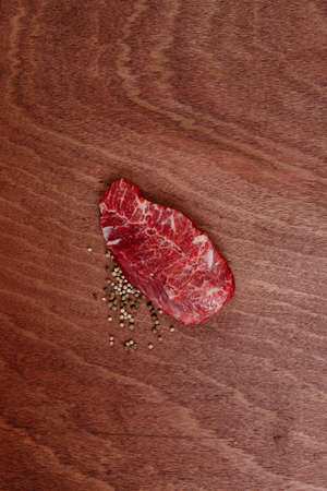 fresh raw beef meat steak with white and green peppercorn spice on walnut table empty space for textの写真素材