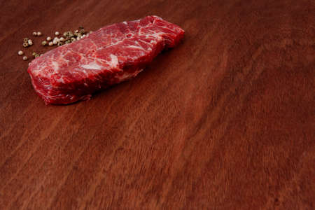 fresh raw beef meat steak with white and green peppercorn spice on walnut table empty space for textの写真素材