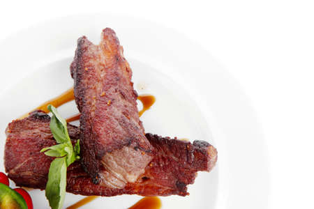 fresh red beef meat steak barbecue garnished vegetable salad and basil  in half of pepper bell on white plate isolated over white backgroundの写真素材