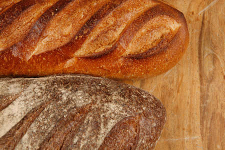 different rye and white flour bread loaf with french fresh baguette on light wooden table backgroundの写真素材