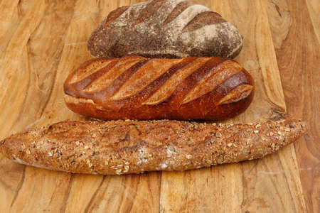 different rye and white flour bread loaf with french fresh baguette on light wooden table background