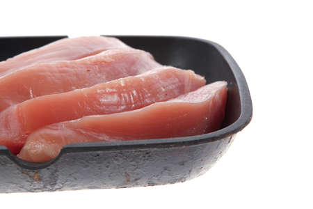 fresh raw turkey pieces on black pan isolated over white backgroundの写真素材