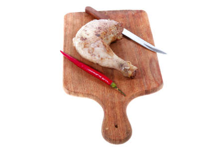 grilled chicken thighs on wooden cut board and red hot chili pepper and stainless steel knife isolated over white backgroundの写真素材