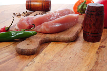fresh raw turkey meat steak with hot sweet pepper dry spices castor and pepperbox on wood cutting boar over tableの写真素材