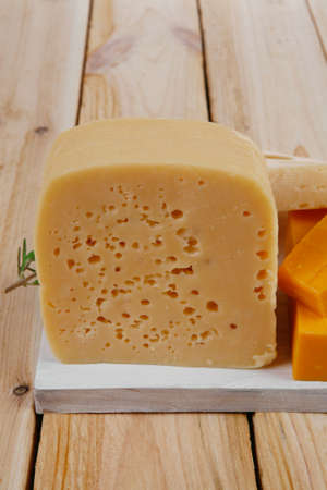 various types of fresh raw aged delicatessen cheese on white plate over light wooden table cheddar edam swissの写真素材