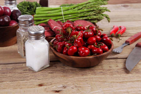 fresh beef meat asparagus greenery spices cutlery wooden table pepper crushed hot chili vegetables...