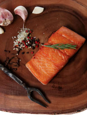 breakfast delicious portion of fresh roast salmon fillet with dry spices garlic and rosemary on wooden plate with black forged handmade fork healthy food diet cooking concept isolated on white background empty spaceの写真素材