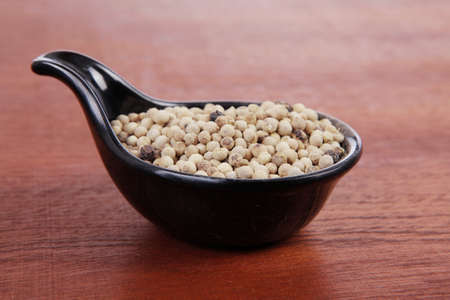 fresh dry peppercorn in small black bowl on wooden table ready to cookの写真素材