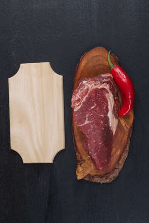 fresh raw piece fillet on small wooden plate with pepper and nameplate space for text on black backgroundの写真素材