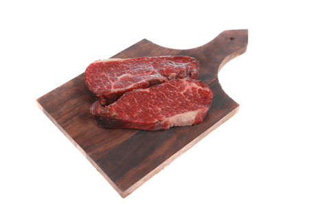 two fresh raw marble beef meat sirloin porterhouse steak on dark wood cut board isolated on white backgroundの写真素材