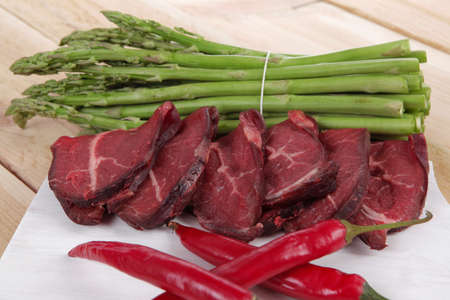 fresh beef meat slices asparagus spices cutlery wooden table pepper hot chili vegetables served garlic light cutting board ready to cookの写真素材