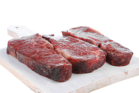 three fresh raw marble beef meat sirloin porterhouse steak on light wood cut board isolated on white backgroundの写真素材