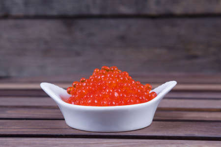 red salmon caviar in white bowls on wooden backgroundの写真素材