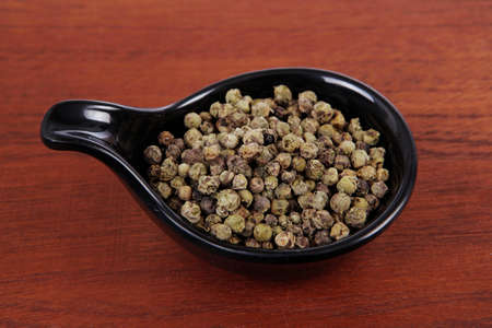 fresh dry peppercorn in small black bowl on wooden table ready to cookの写真素材