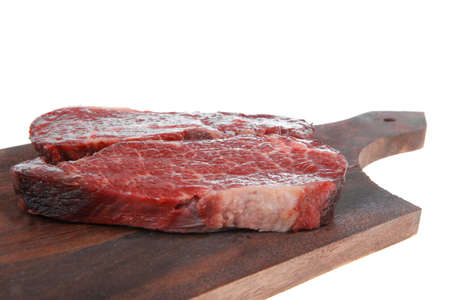 two fresh raw marble beef meat sirloin porterhouse steak on dark wood cut board isolated on white backgroundの写真素材