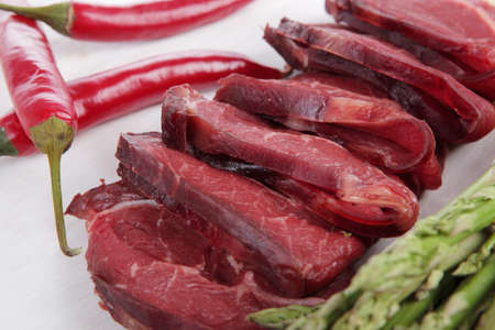 fresh beef meat slices asparagus spices cutlery wooden table pepper hot chili vegetables served garlic light cutting board ready to cookの写真素材
