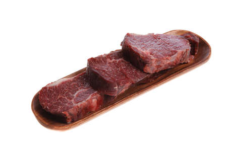 three fresh raw marble beef meat sirloin porterhouse steak on long wooden tray isolated on white backgroundの写真素材