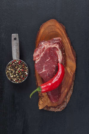 fresh raw beef piece fillet on small wooden plate with pepper peppercorns and nameplate space for text on black backgroundの写真素材