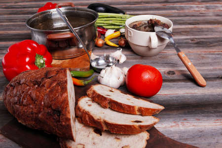 home style beef meat soup vintage country wood table asparagus pepper bell spices bread garlic cutlery eggplantの写真素材