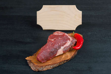 fresh raw piece fillet on small wooden plate with pepper and nameplate space for text on black backgroundの写真素材