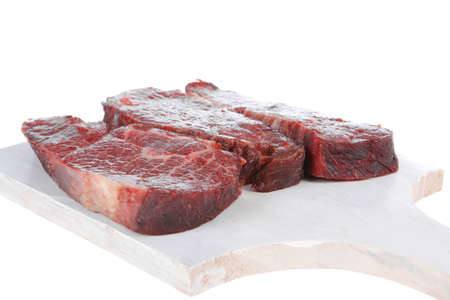 three fresh raw marble beef meat sirloin porterhouse steak on light wood cut board isolated on white backgroundの写真素材