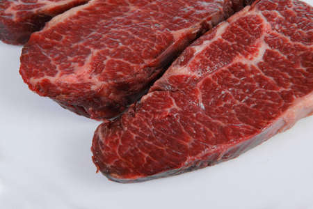 three fresh raw marble beef meat sirloin porterhouse steak on big ceramic cooking pan isolated on white backgroundの写真素材