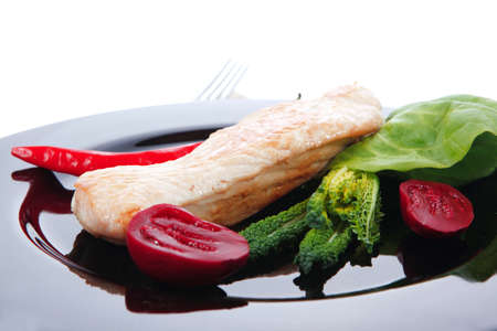 fresh roast turkey meat steak fillet with red hot pepper and green lettuce salad kale on black plate isolated over white backgroundの写真素材