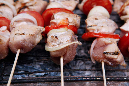fresh turkey pink brisket shish kebab on wooden skewers with tomatoes over barbecue brazier full burned charcoalの写真素材
