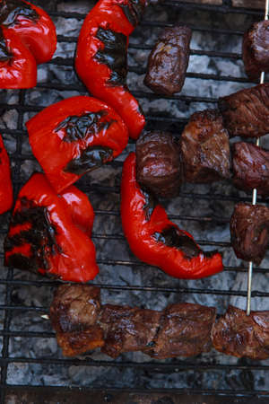 fresh raw beef fillet steak red meat brisket on skewers with grilled pepper barbecue brazier grid full burned charcoal selective focusの写真素材