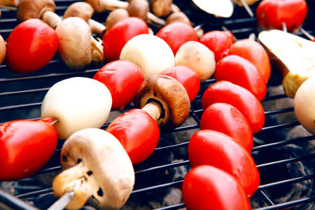 fresh raw tomatoes onion mushroom eggplant on skewers over charcoal on grid over brazier grillの写真素材