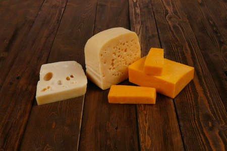 various types of fresh raw aged delicatessen cheese on wooden table cheddar edam swissの写真素材
