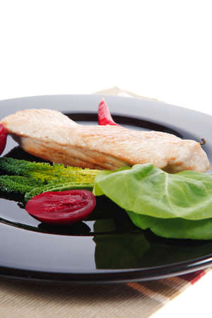 fresh roast turkey meat steak fillet with red hot pepper and green lettuce salad kale on black plate isolated over white backgroundの写真素材