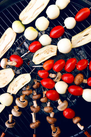 fresh raw tomatoes onion mushroom eggplant on skewers over charcoal on grid over brazier grillの写真素材