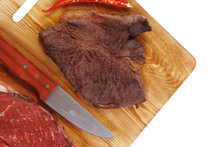 grilled and raw beef steak fillet meat with knife on wooden board isolated over white backgroundの写真素材
