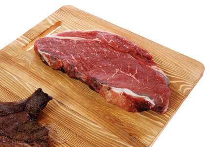 grilled and raw beef steak fillet meat on wooden board isolated over white backgroundの写真素材