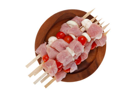 fresh raw meat fillet shish kebab turkey pork pink on skewers tomatoes mushrooms on wooden dish isolated over white backgroundの写真素材