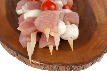 fresh raw meat fillet shish kebab turkey pork pink on skewers tomatoes mushrooms on wooden kitchen plate isolated over white backgroundの写真素材
