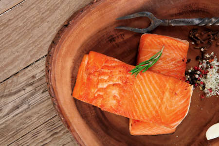 breakfast delicious portion of fresh roast salmon fillet with dry spices garlic and rosemary on wooden plate with black forged handmade fork healthy food diet cooking conceptの写真素材