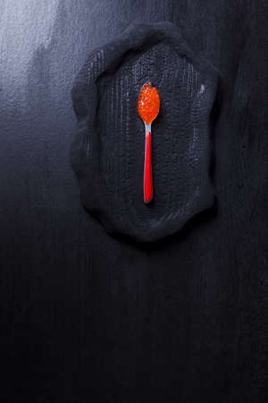 fresh raw red salmon caviar in white crystal bowls with small spoon on blackwooden backgroundの写真素材