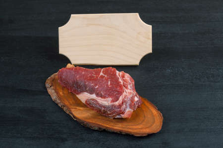 fresh raw piece fillet on small wooden plate with pepper and nameplate space for text on black backgroundの写真素材
