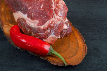 fresh raw piece fillet on small wooden plate with pepper and nameplate space for text on black backgroundの写真素材